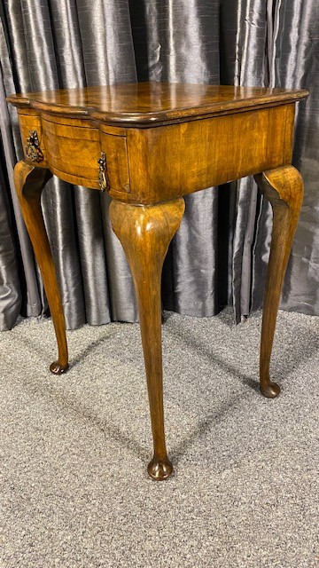 A Queen Anne style walnut occasional table featuring slender cabriole legs, pad feet, and a single drawer fitted with two ornate brass drop handles. View IV