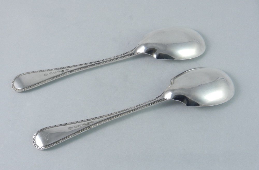 A pair of antique silver-plated fruit spoons featuring bright-cut engraved starburst patterns on the bowls and patterned borders on the handles. View II