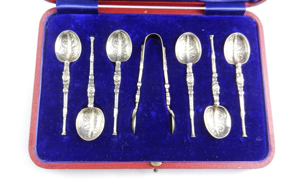 An open red presentation case lined with blue silk and velvet holding six silver-gilt teaspoons and a pair of matching sugar tongs. View II