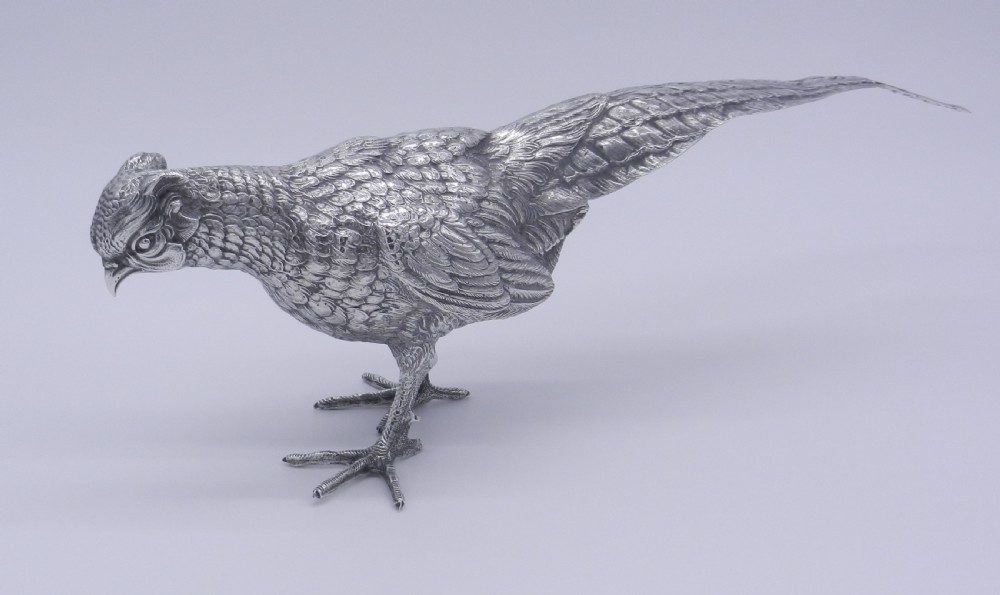A pair of detailed cast silver pheasant figurines depicted standing in dynamic poses with extended tail feathers. View IV