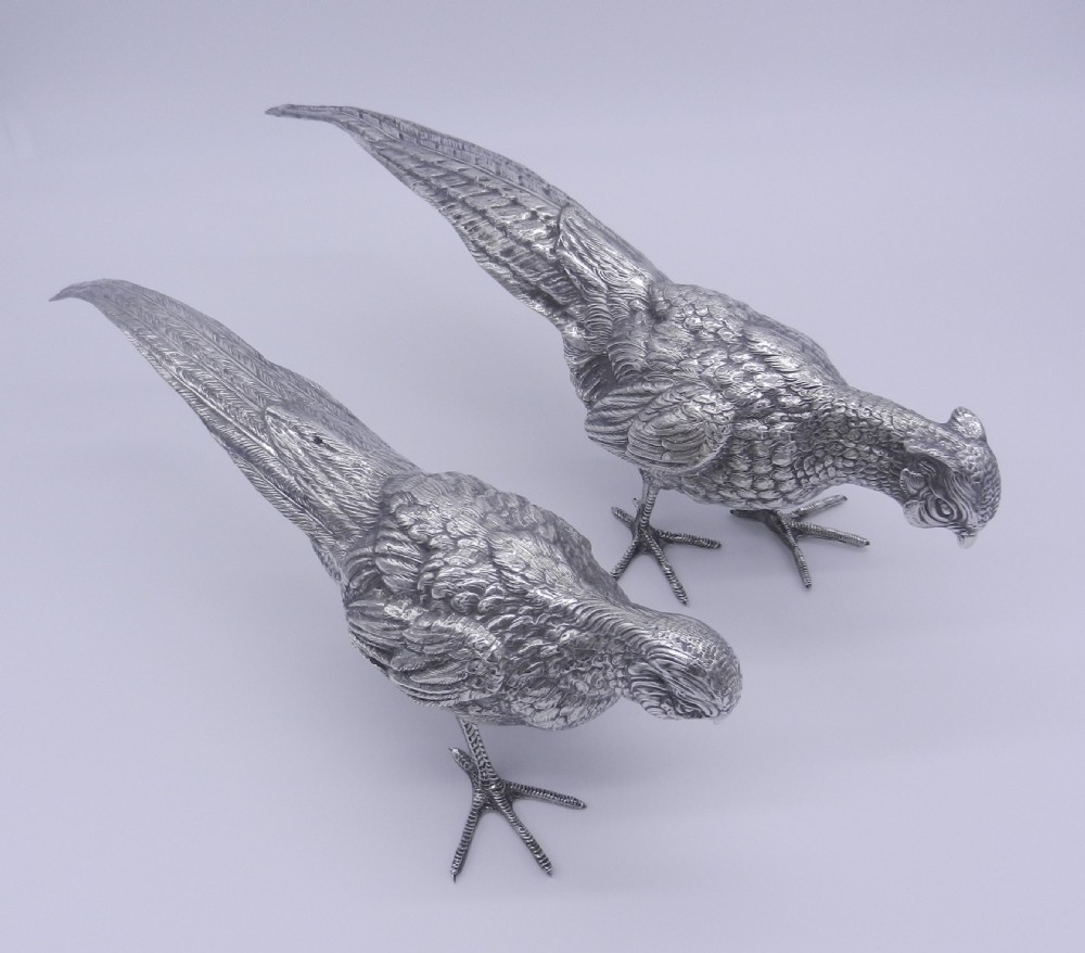 A pair of detailed cast silver pheasant figurines depicted standing in dynamic poses with extended tail feathers. View VIII