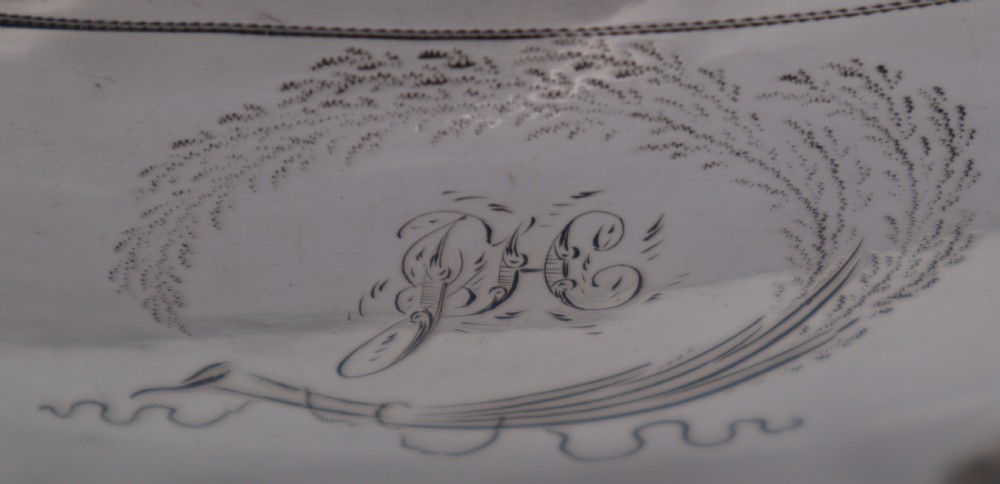 An antique sterling silver teapot with engraved foliate motifs, an oblong body, ball feet, and a hinged lid. View IV
