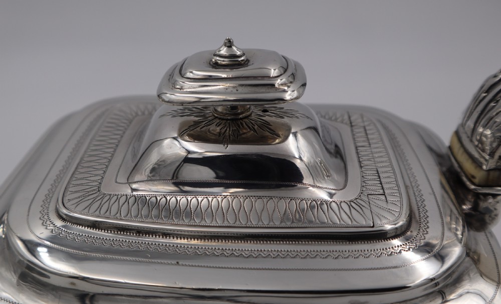 An antique sterling silver teapot with engraved foliate motifs, an oblong body, ball feet, and a hinged lid. View VII