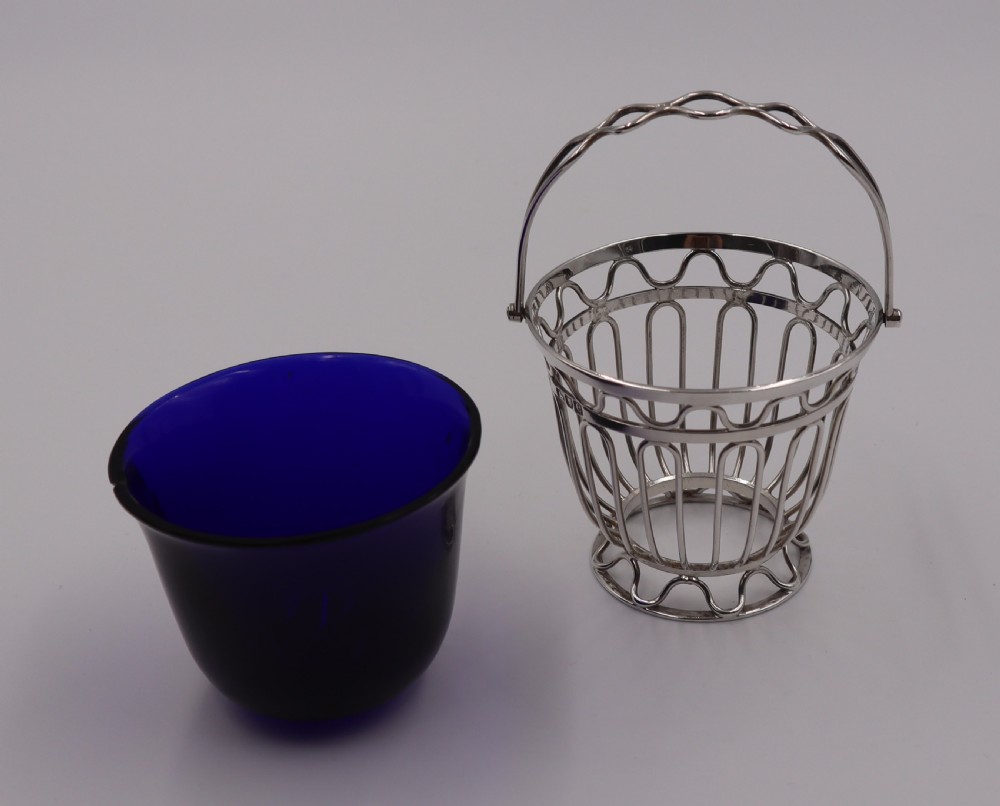 An antique silver wirework sugar basket featuring a swing handle and a deep cobalt blue glass liner. View II