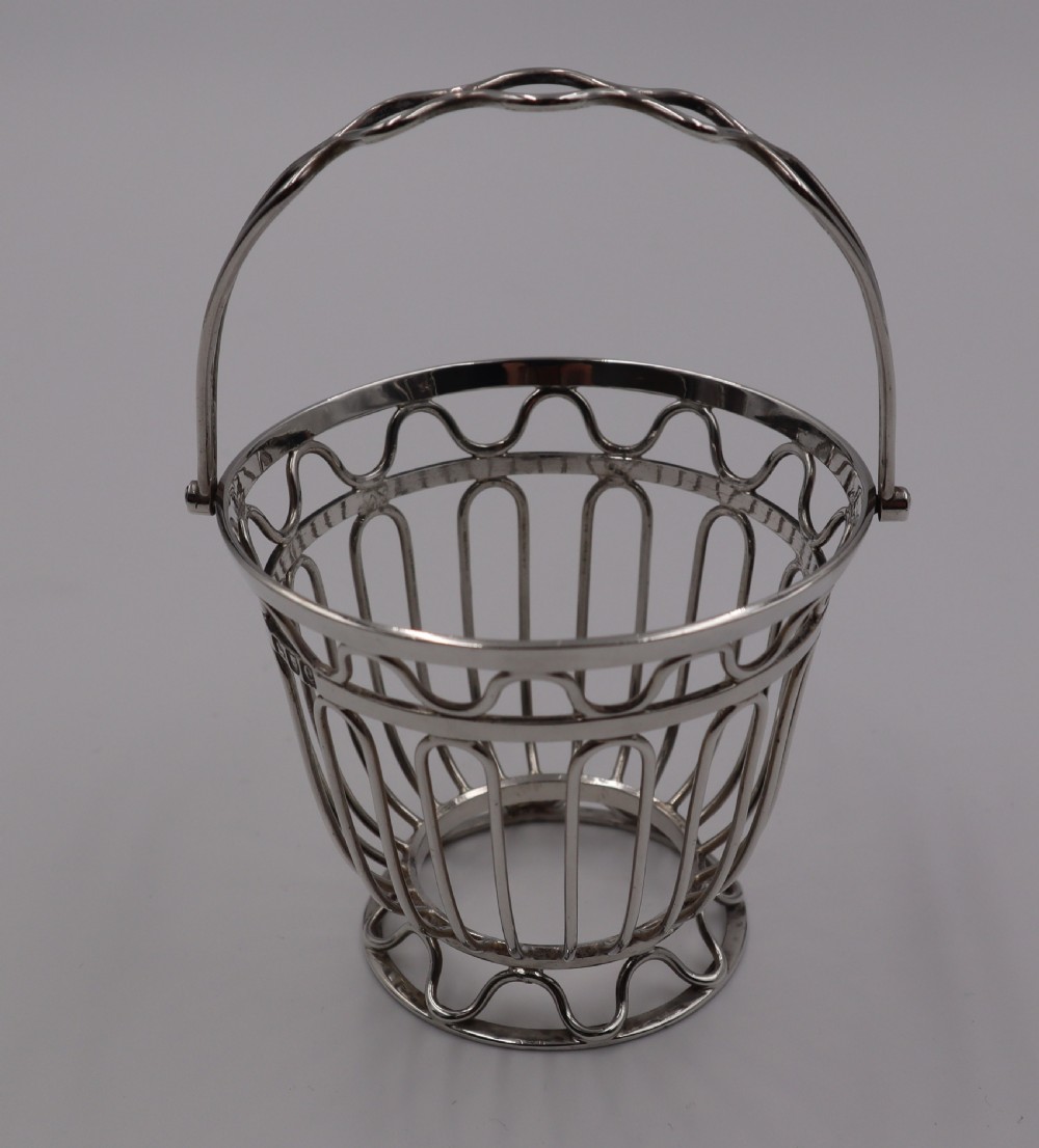 An antique silver wirework sugar basket featuring a swing handle and a deep cobalt blue glass liner. View III