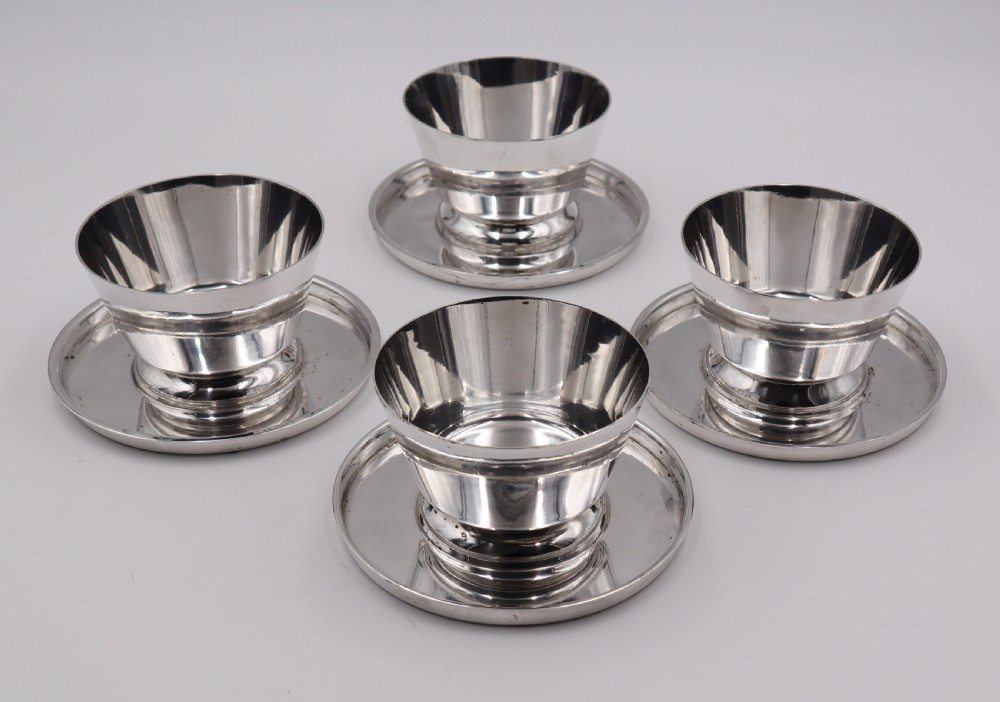 A set of four silverplated Art Deco dessert dishes featuring flared rims, stepped bases, and matching circular saucers.