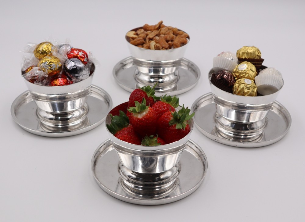 A set of four silverplated Art Deco dessert dishes featuring flared rims, stepped bases, and matching circular saucers. View II