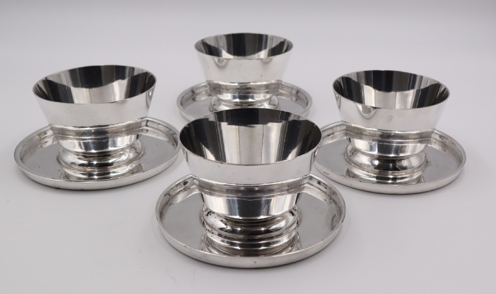 A set of four silverplated Art Deco dessert dishes featuring flared rims, stepped bases, and matching circular saucers. View III