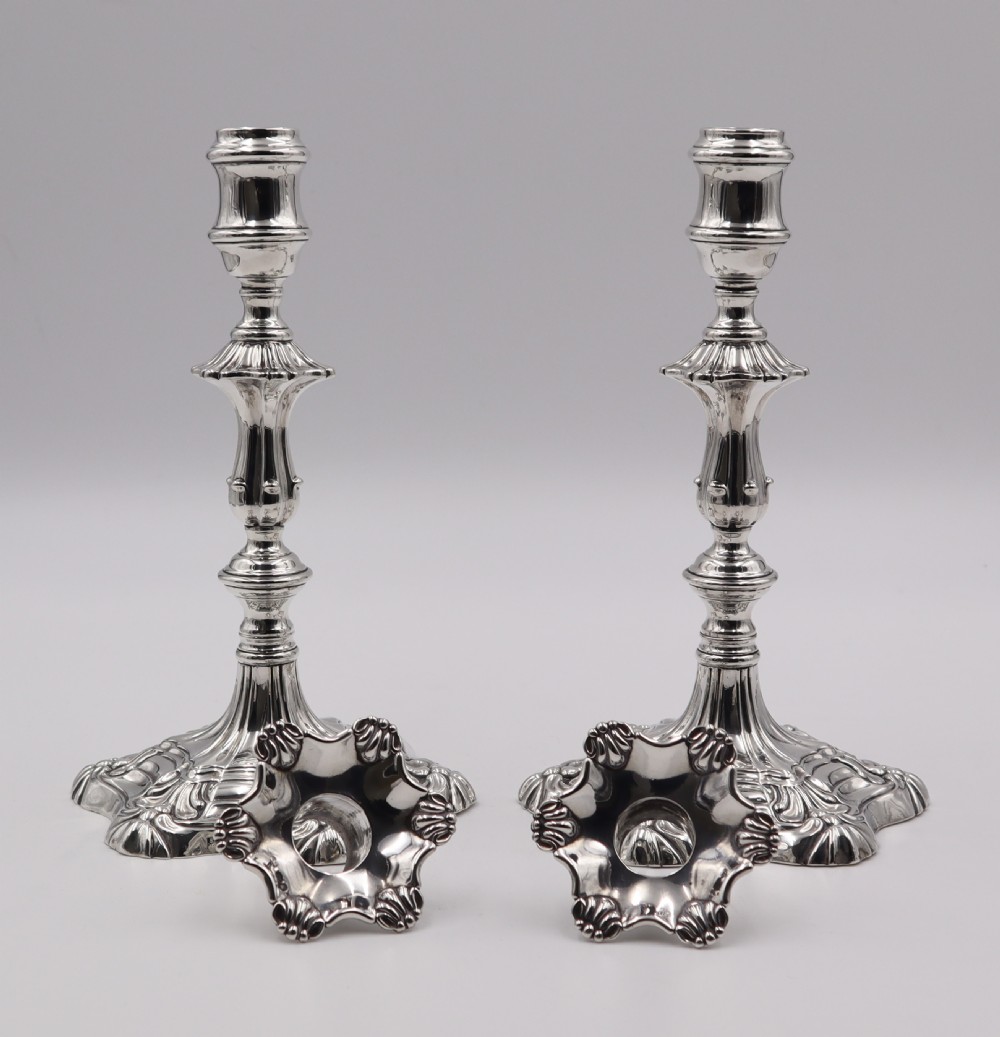 A pair of polished silver candlesticks featuring knopped stems, scalloped nozzles, and moulded shell-shaped bases with visible assay hallmarks. View II