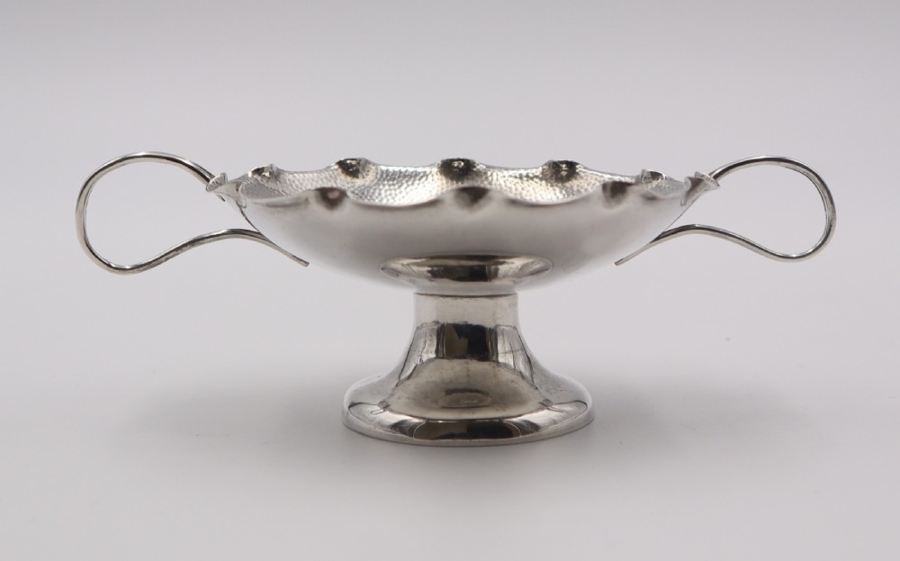 An antique Chinese silver pedestal bowl featuring a hand-hammered texture, scalloped rim, twin loop handles, and a flared pedestal base. View II