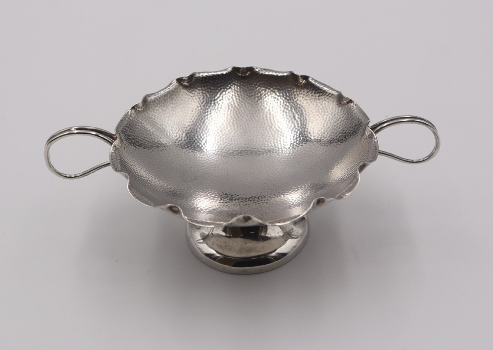 An antique Chinese silver pedestal bowl featuring a hand-hammered texture, scalloped rim, twin loop handles, and a flared pedestal base. View III