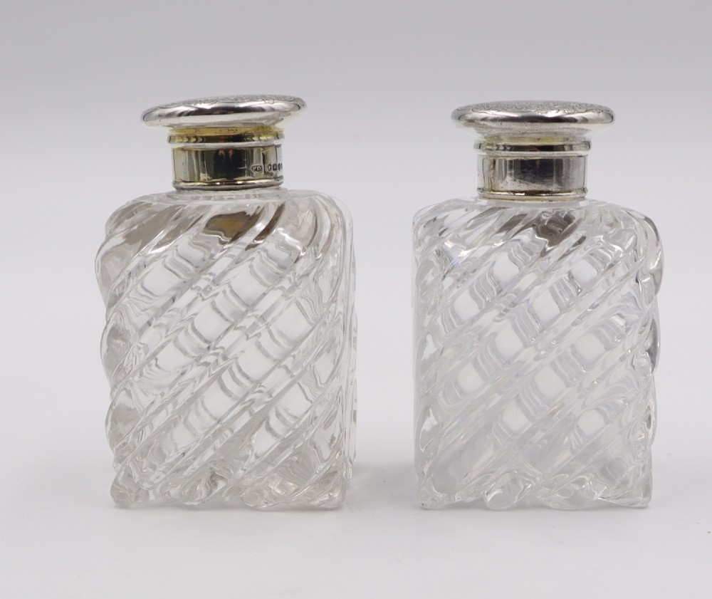 A pair of clear cut-glass perfume bottles featuring diagonal swirl moulding and engraved silver caps. View III