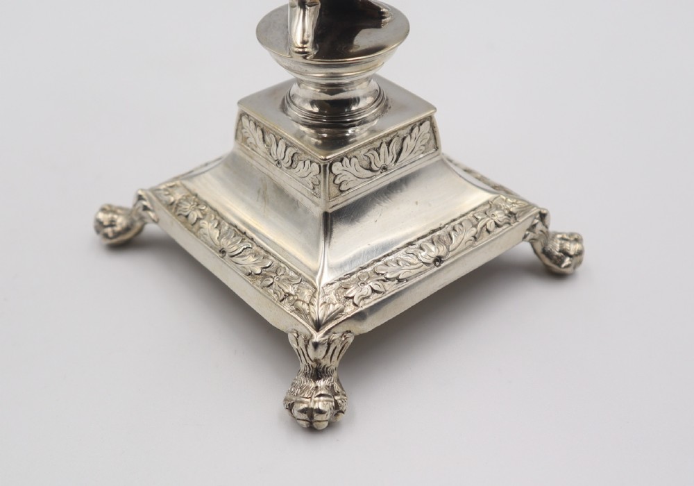 An antique silver figural toothpick holder depicting a woman balancing a woven basket on her head atop a square pedestal base with decorative feet. View VI