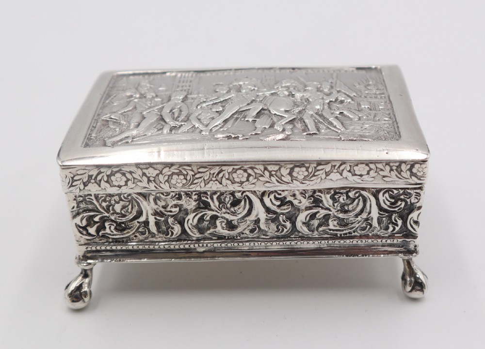 A rectangular silver trinket box featuring an embossed relief scene of Napoleon on the lid, ornate filigree side panels, and small raised ball feet. View II