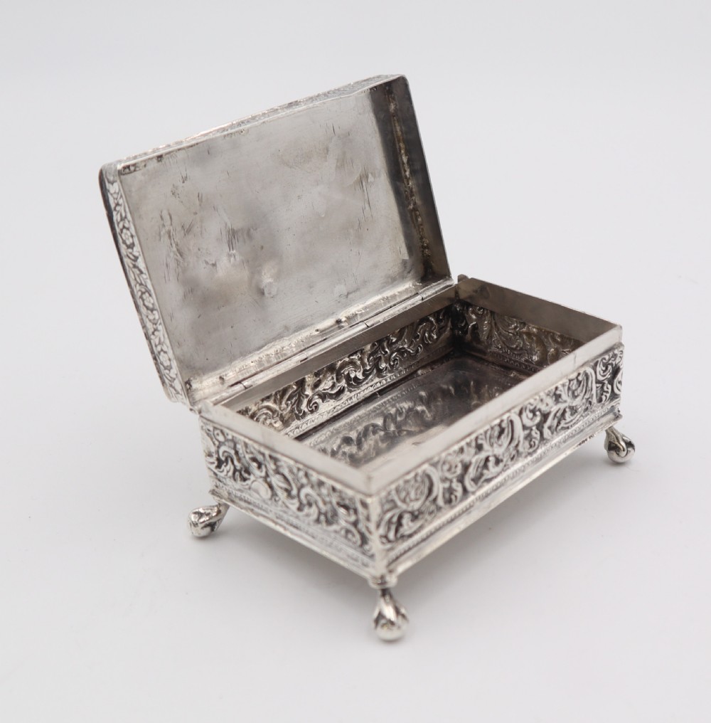 A rectangular silver trinket box featuring an embossed relief scene of Napoleon on the lid, ornate filigree side panels, and small raised ball feet. View IV