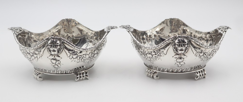 A pair of ornate antique silver bowls featuring embossed lion head masks, floral swags, gadrooned bases, and scroll feet. View II