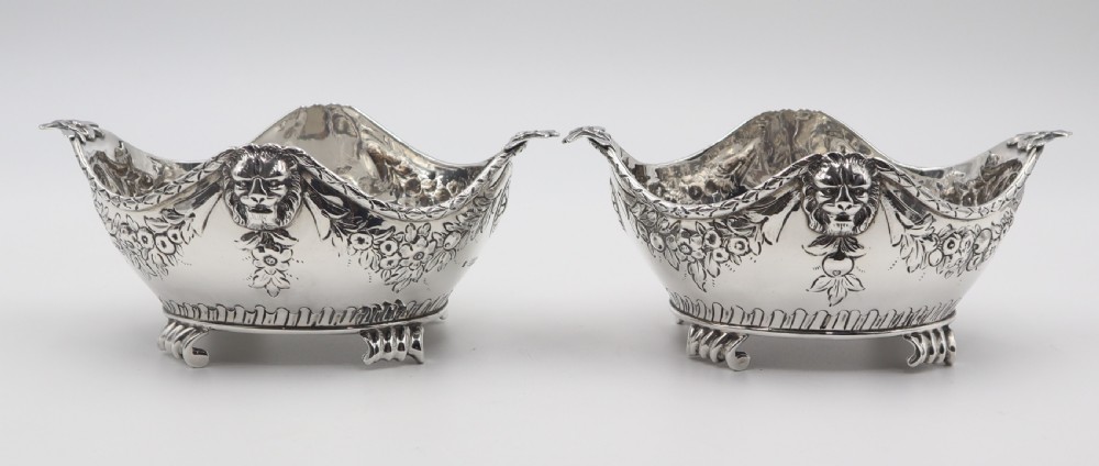 A pair of ornate antique silver bowls featuring embossed lion head masks, floral swags, gadrooned bases, and scroll feet. View III