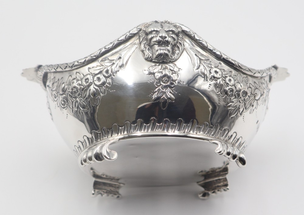 A pair of ornate antique silver bowls featuring embossed lion head masks, floral swags, gadrooned bases, and scroll feet. View IV