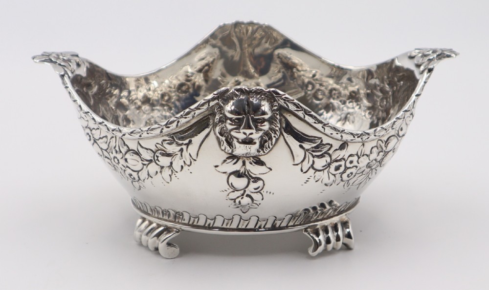 A pair of ornate antique silver bowls featuring embossed lion head masks, floral swags, gadrooned bases, and scroll feet. View VII