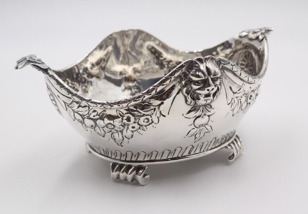 A pair of ornate antique silver bowls featuring embossed lion head masks, floral swags, gadrooned bases, and scroll feet. View IX