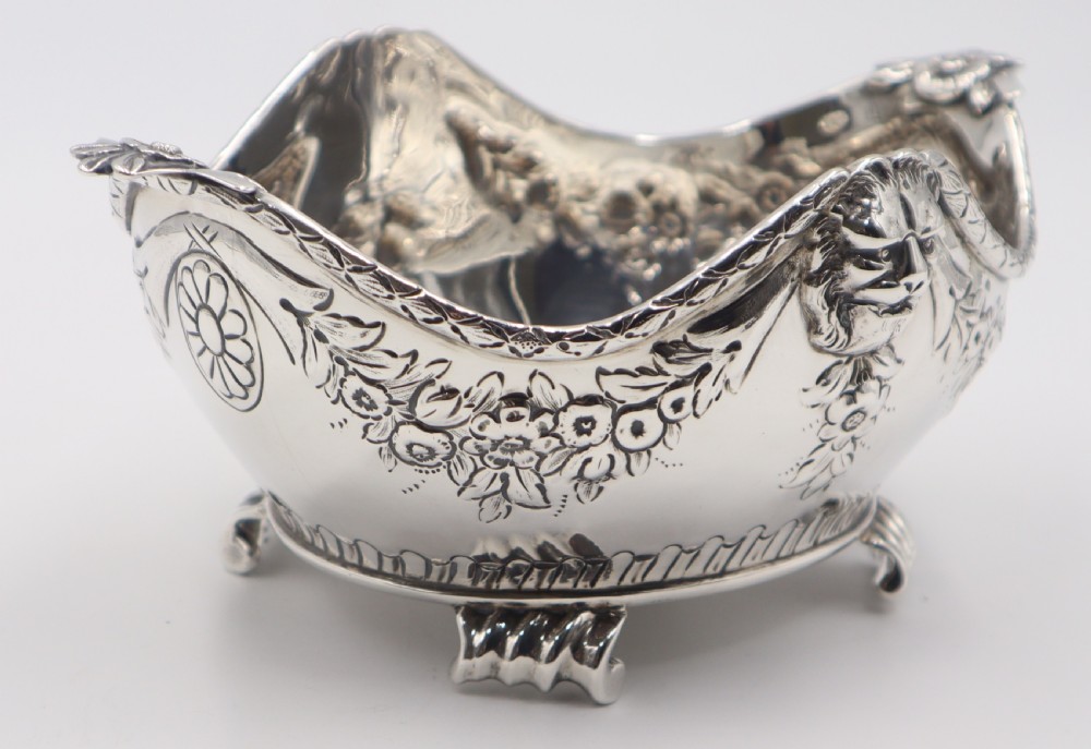 A pair of ornate antique silver bowls featuring embossed lion head masks, floral swags, gadrooned bases, and scroll feet. View X