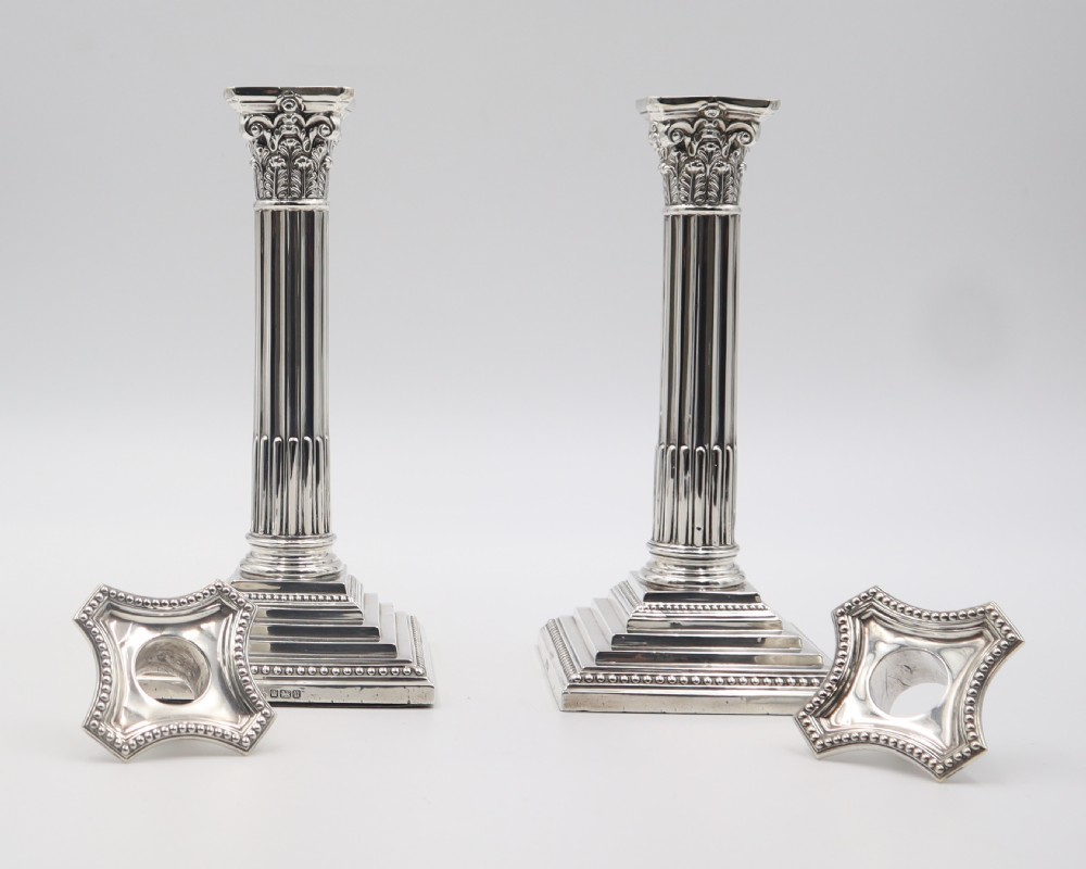A pair of antique sterling silver candlesticks styled as fluted Corinthian columns resting on stepped square bases with beaded trim. View II