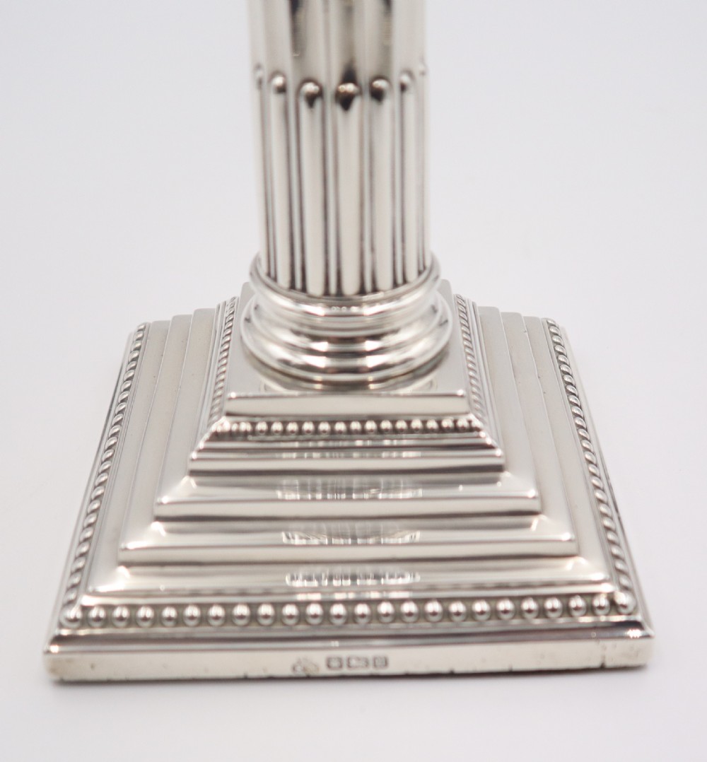 A pair of antique sterling silver candlesticks styled as fluted Corinthian columns resting on stepped square bases with beaded trim. View VII