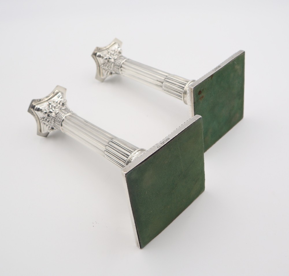 A pair of antique sterling silver candlesticks styled as fluted Corinthian columns resting on stepped square bases with beaded trim. View VIII