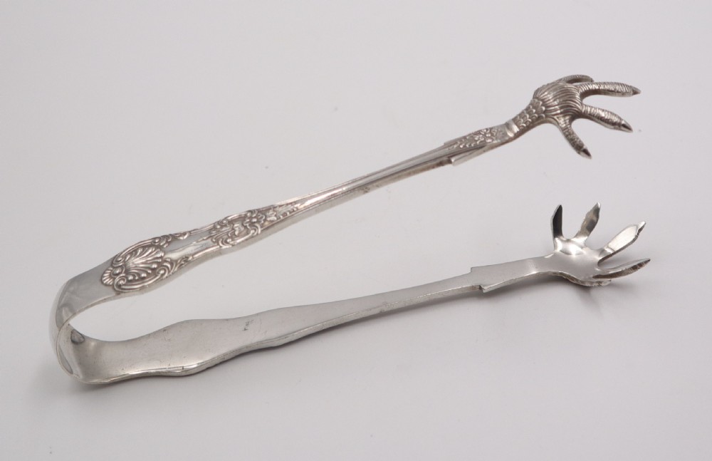 A pair of antique silverplate ice tongs featuring a sprung bow handle with shell reliefs and claw-shaped grips.