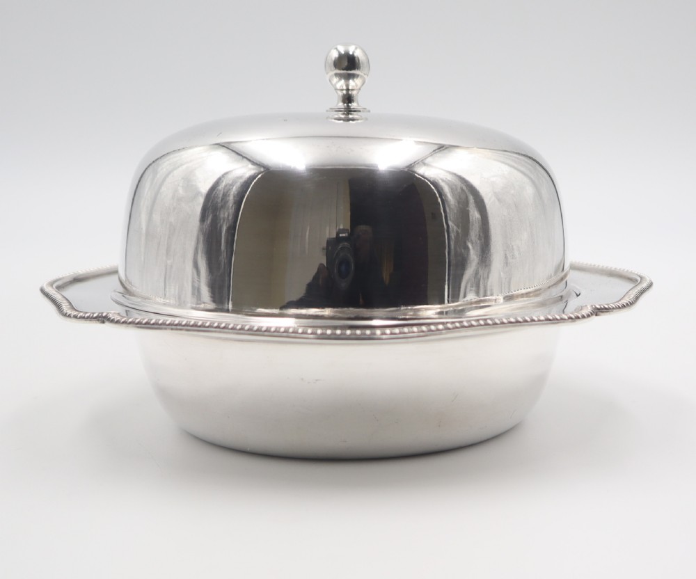 An antique silverplated muffin dish featuring a domed lid with a ball finial and a circular tray with a beaded edge. View V