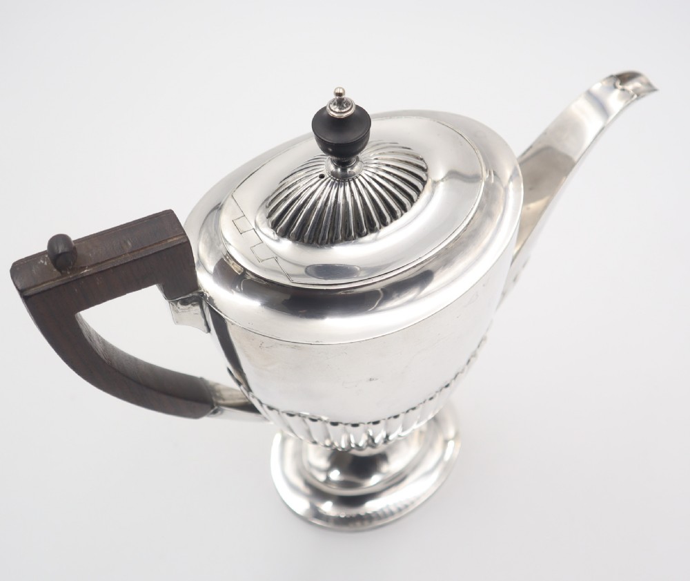 A four-piece antique silverplate tea and coffee set featuring fluted lower bodies and dark wooden handles on a plain white background. View IV