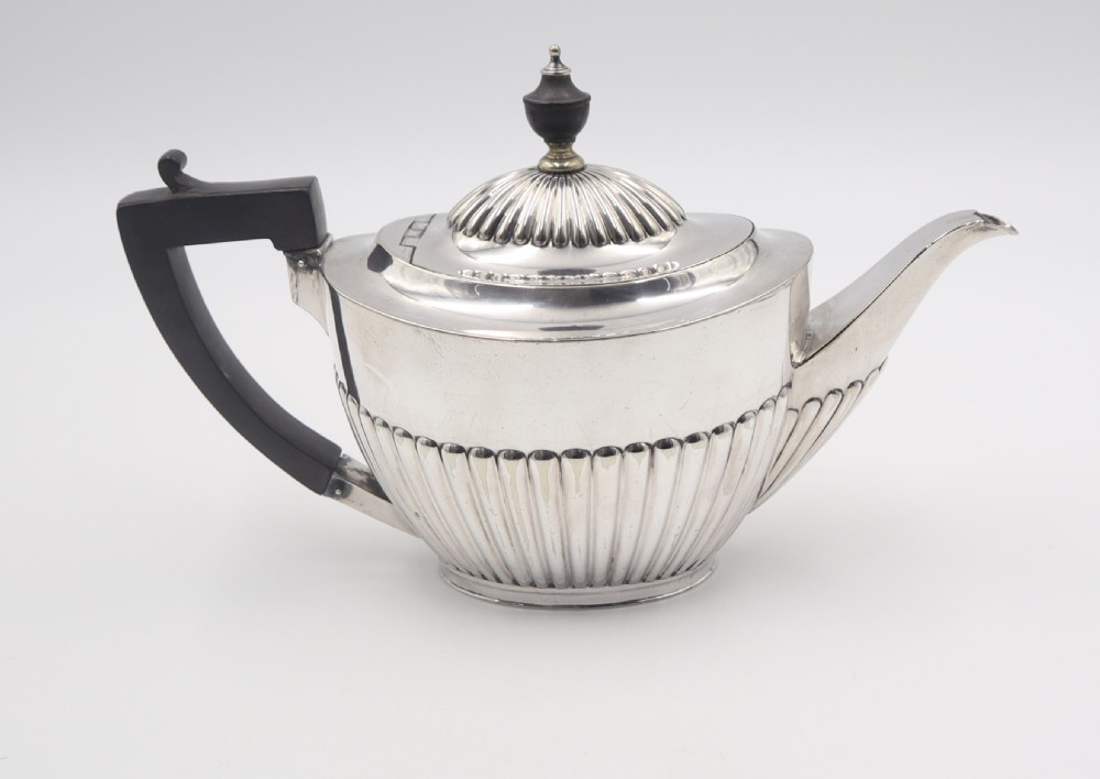 A four-piece antique silverplate tea and coffee set featuring fluted lower bodies and dark wooden handles on a plain white background. View V