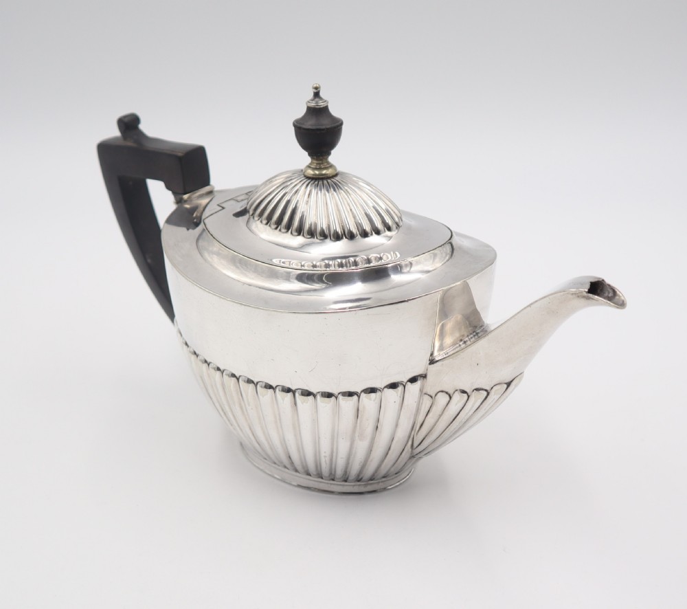 A four-piece antique silverplate tea and coffee set featuring fluted lower bodies and dark wooden handles on a plain white background. View VI