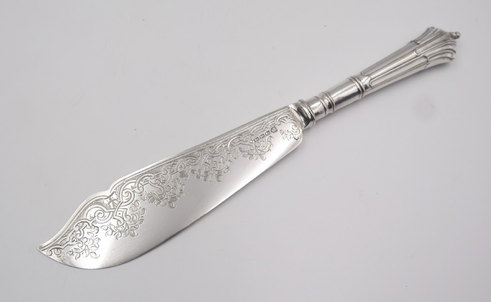 A set of antique silver-plated fish servers featuring an engraved serving knife and a matching four-tined fork with fluted handles. View V