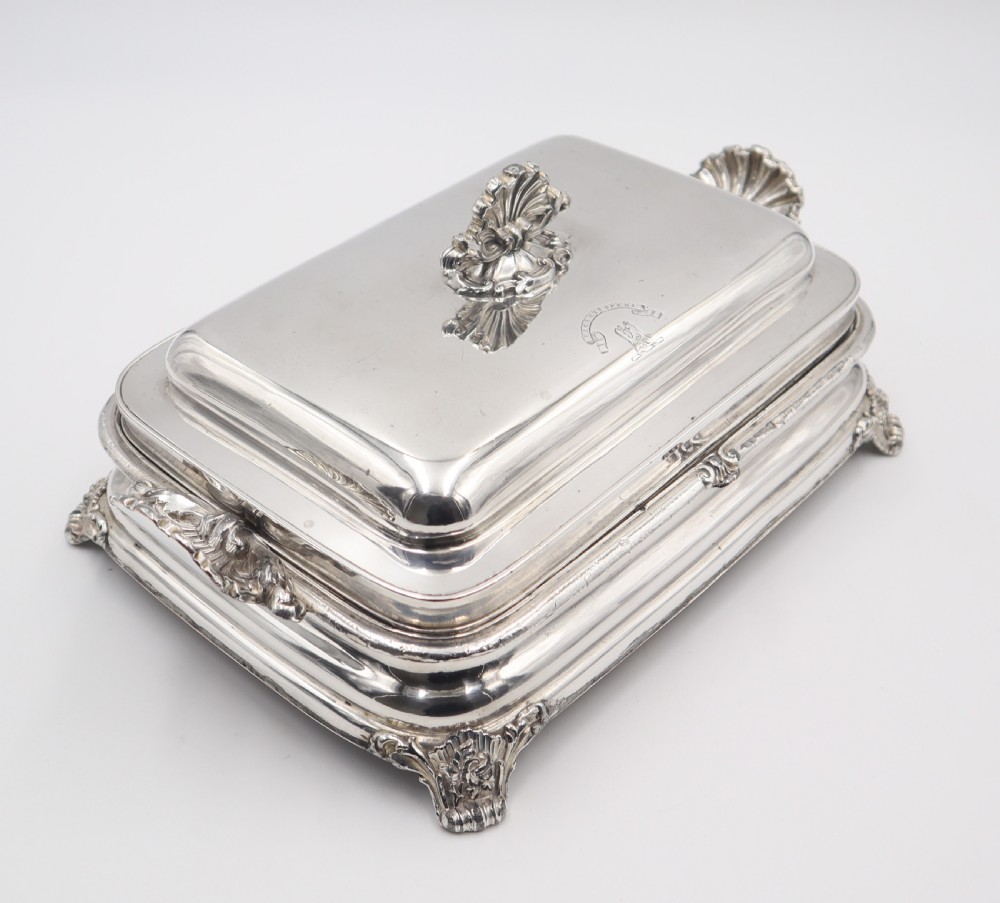 A rectangular silver-plated warming entree dish featuring shell-form handles, a domed lid with a shell finial, and a raised pedestal base. View II
