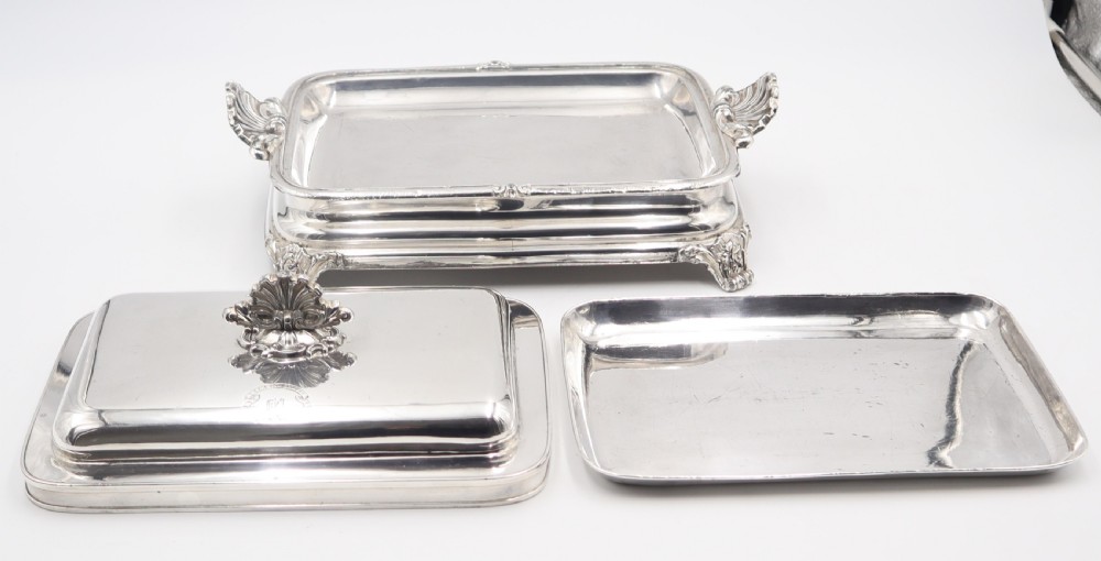 A rectangular silver-plated warming entree dish featuring shell-form handles, a domed lid with a shell finial, and a raised pedestal base. View III