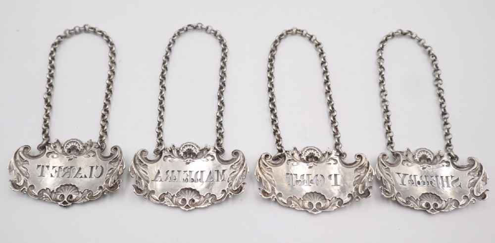 A set of four silver decanter labels featuring shell and scroll borders, each suspended by a chain and inscribed with Claret, Madeira, Port, and Sherry. View II