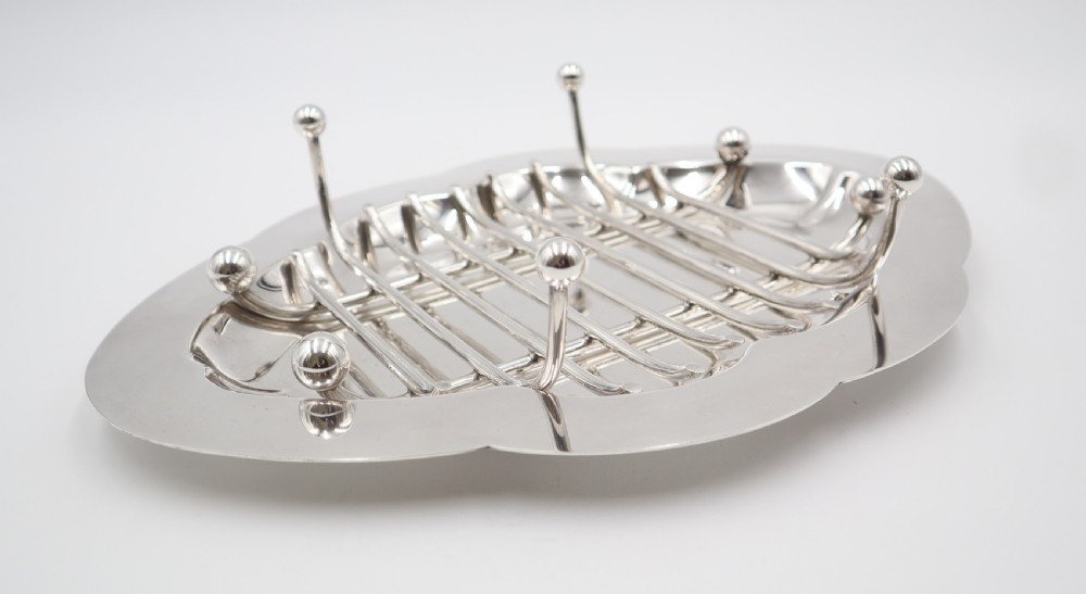 An oval silver-plated dish featuring a scalloped rim and a removable central wire rack supported by small spherical feet. View III
