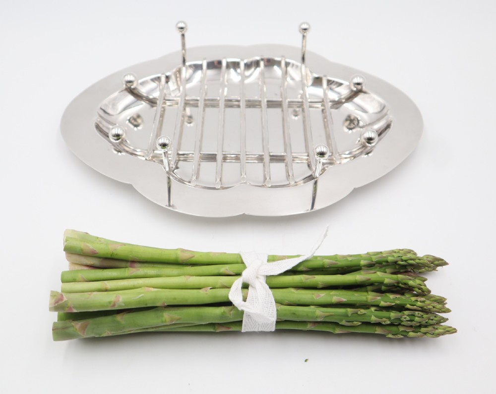 An oval silver-plated dish featuring a scalloped rim and a removable central wire rack supported by small spherical feet. View IV