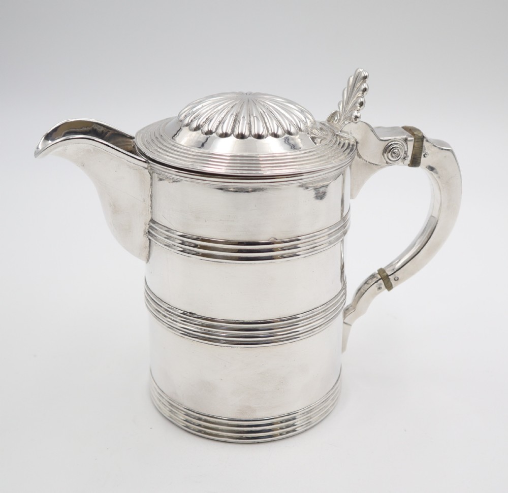 An antique silver Old Sheffield plate beer jug featuring reeded horizontal bands, a fluted hinged lid, an engraved heraldic crest, and a curved handle. View II