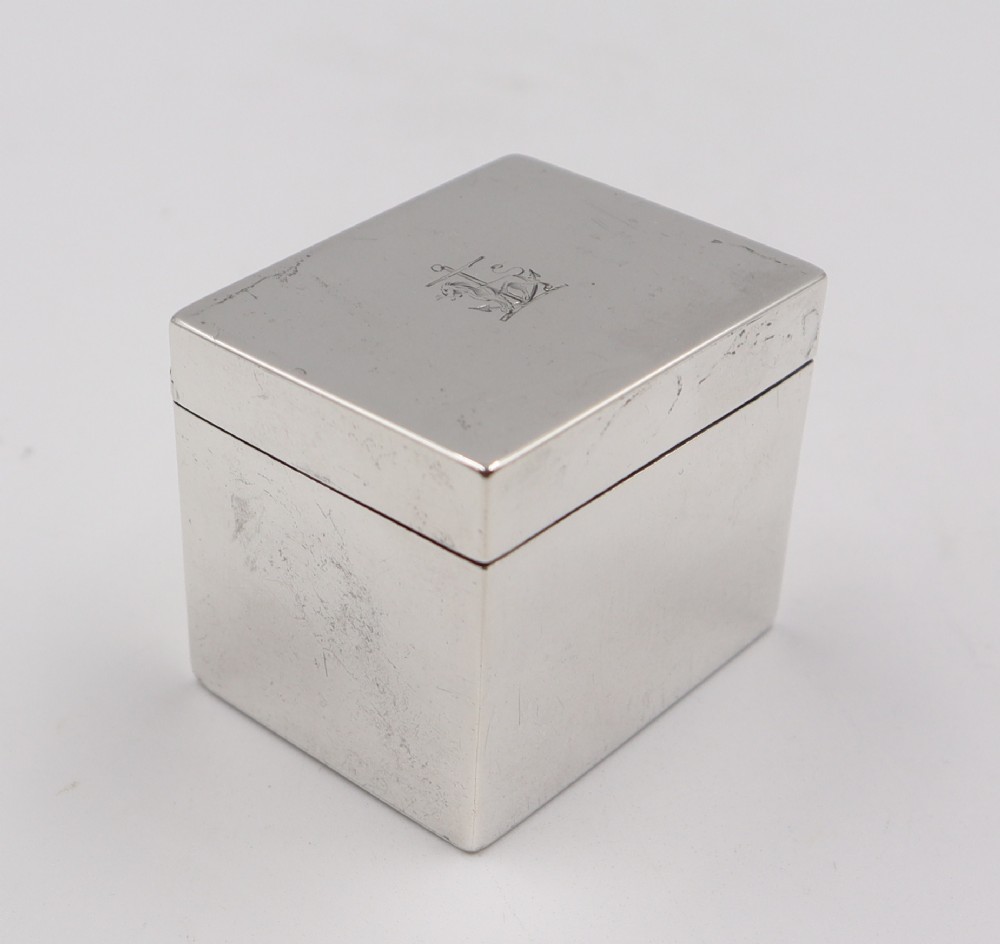 A small rectangular antique sterling silver box with a hinged lid engraved with a heraldic crest.