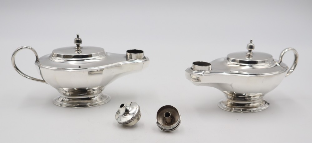 A pair of polished silver table lighters designed in the traditional shape of classical oil lamps with curved loop handles and pedestal bases. View III