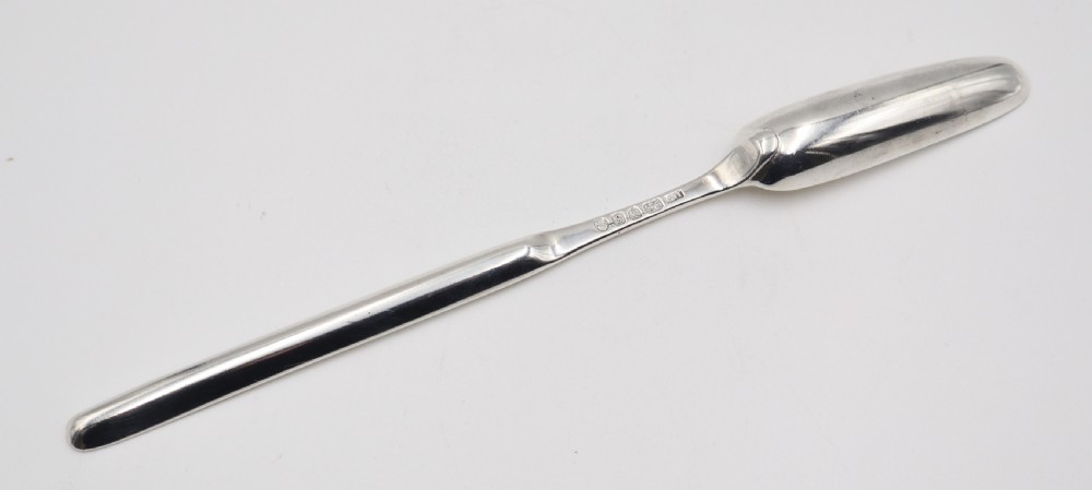 An elongated double-ended sterling silver marrow scoop with a narrow trough at one end and a broader trough at the other. View IV