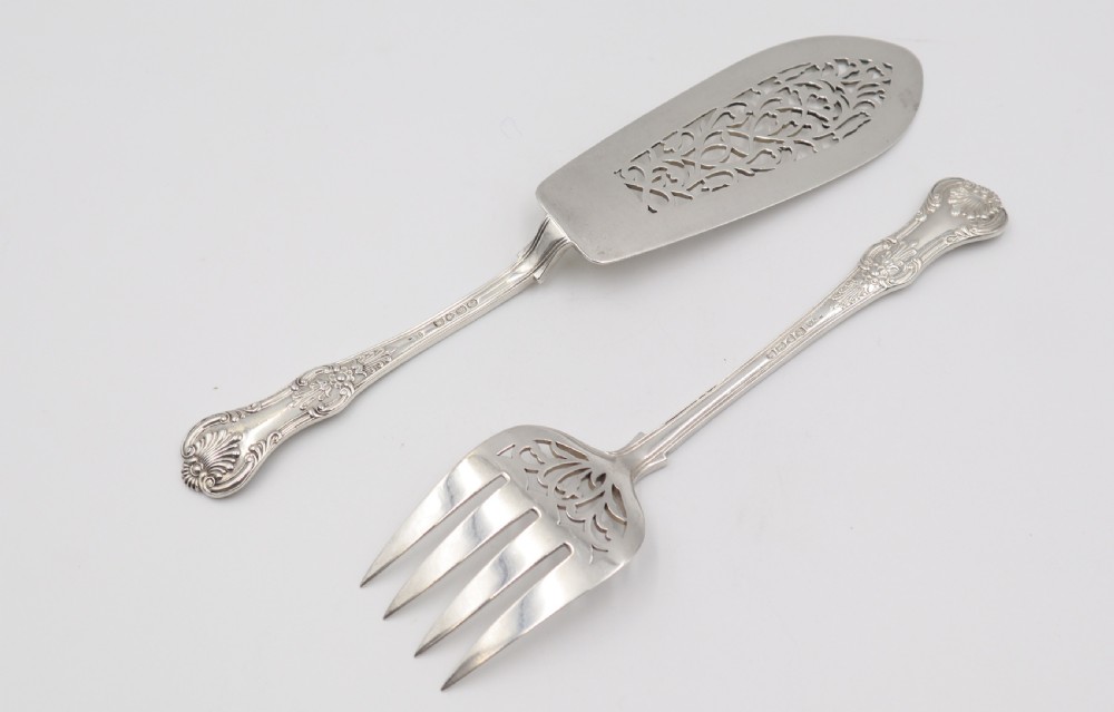 A two-piece set of silver fish servers comprising a pierced blade slice and a matching four-tined fork with decorative scroll handles. View IX