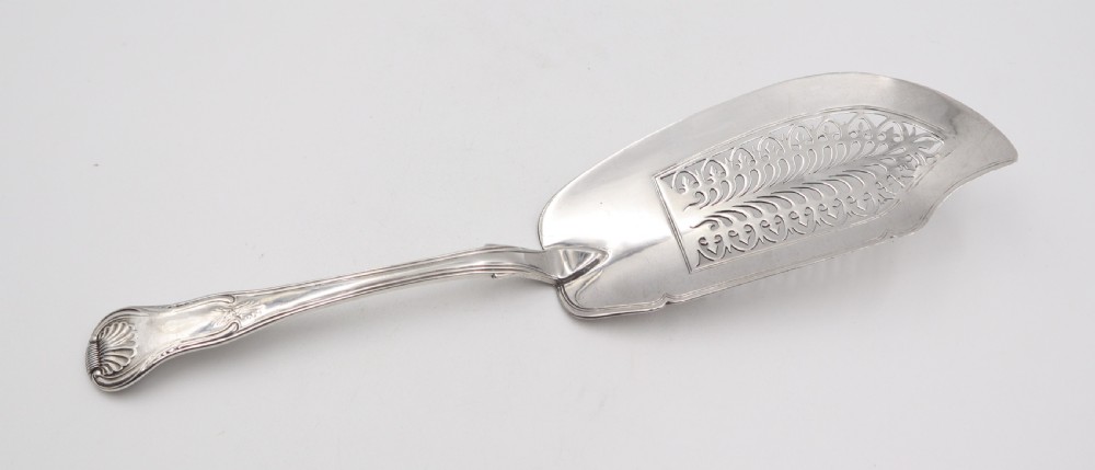 An antique sterling silver fish slice featuring a pierced engraved blade and a fiddle and shell pattern handle.