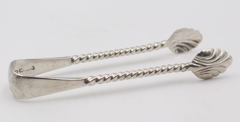 A pair of silver sugar tongs featuring a flexible plain bow, spiral twisted arms, and shell-shaped grips.