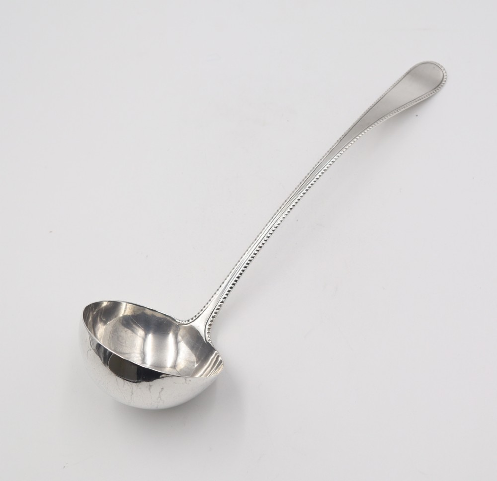 An antique silver soup ladle featuring a beaded rim pattern along the long curved handle and a deep circular bowl. View III