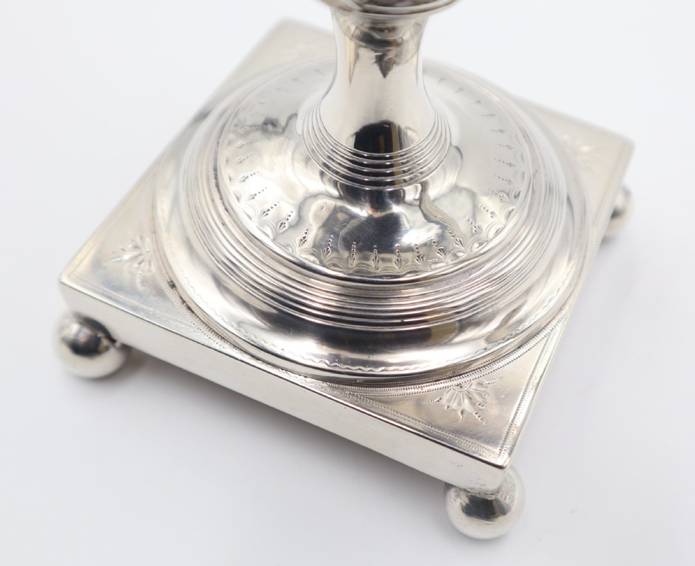 An antique silver tea urn featuring high loop handles, engraved floral bands, a front tap, and a square pedestal base supported by ball feet. View IV