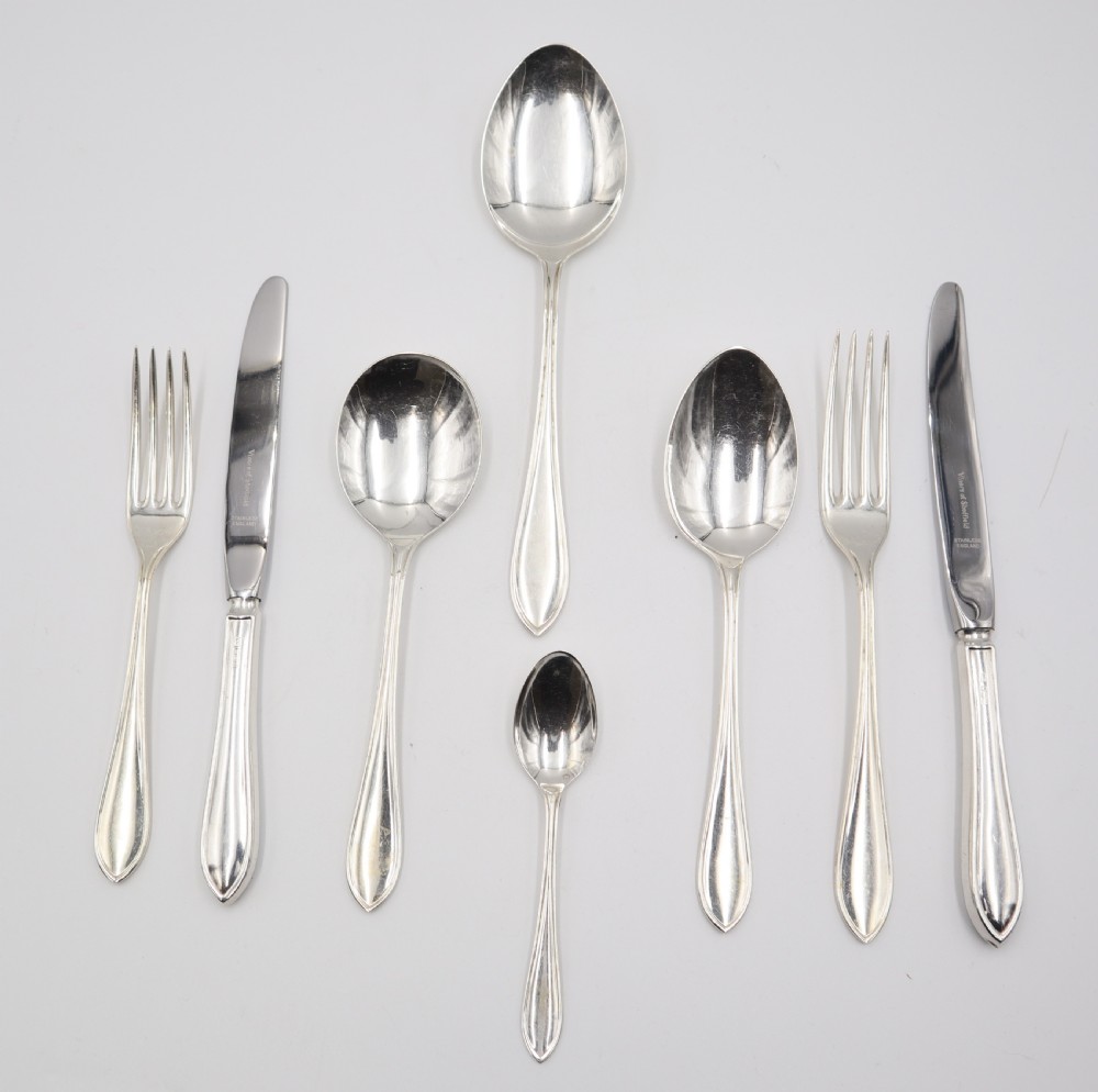 A comprehensive silver cutlery set containing dinner knives, forks, soup spoons, and dessert spoons laid out flat on a light grey background. View II