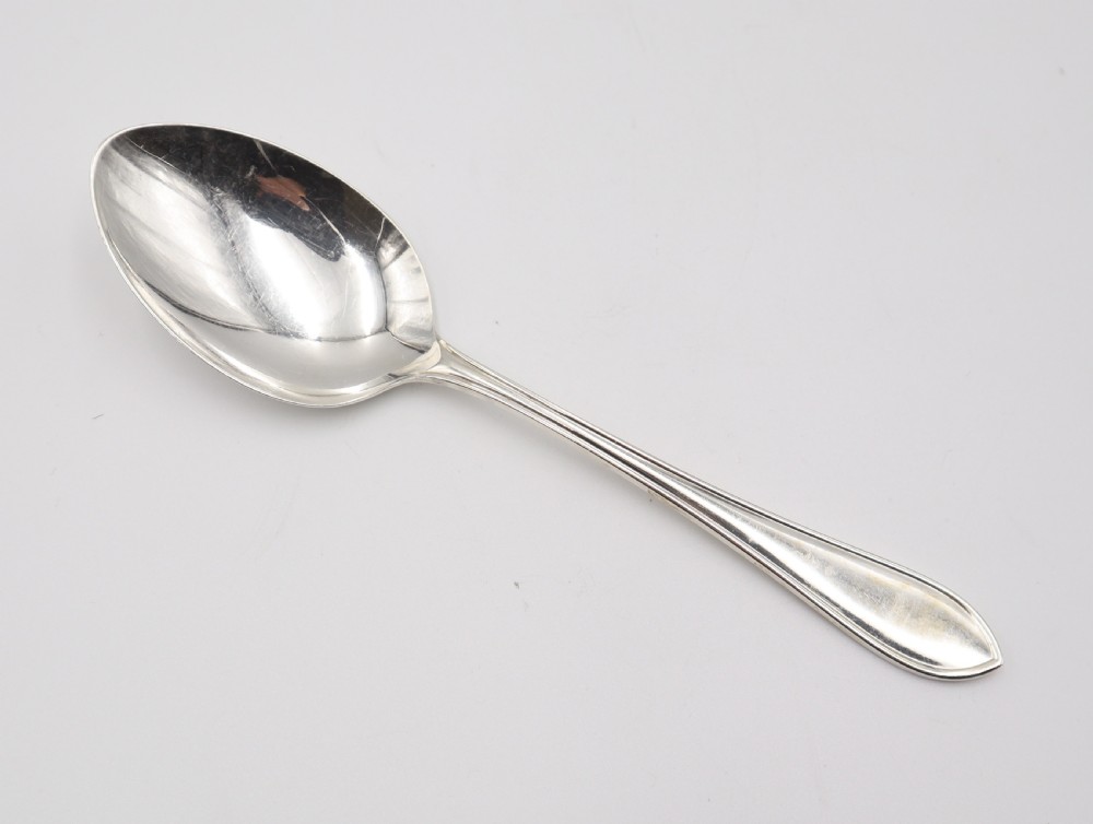 A comprehensive silver cutlery set containing dinner knives, forks, soup spoons, and dessert spoons laid out flat on a light grey background. View IV